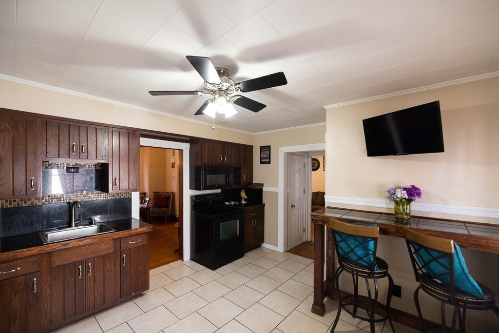 61 Dwight Road Springfield, MA 01108 - Photo 5 of 34 a kitchen with stainless steel appliances kitchen island granite countertop a sink dishwasher a dining table and chairs with wooden floor
