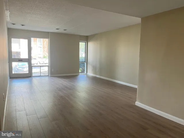an empty room with wooden floor and windows