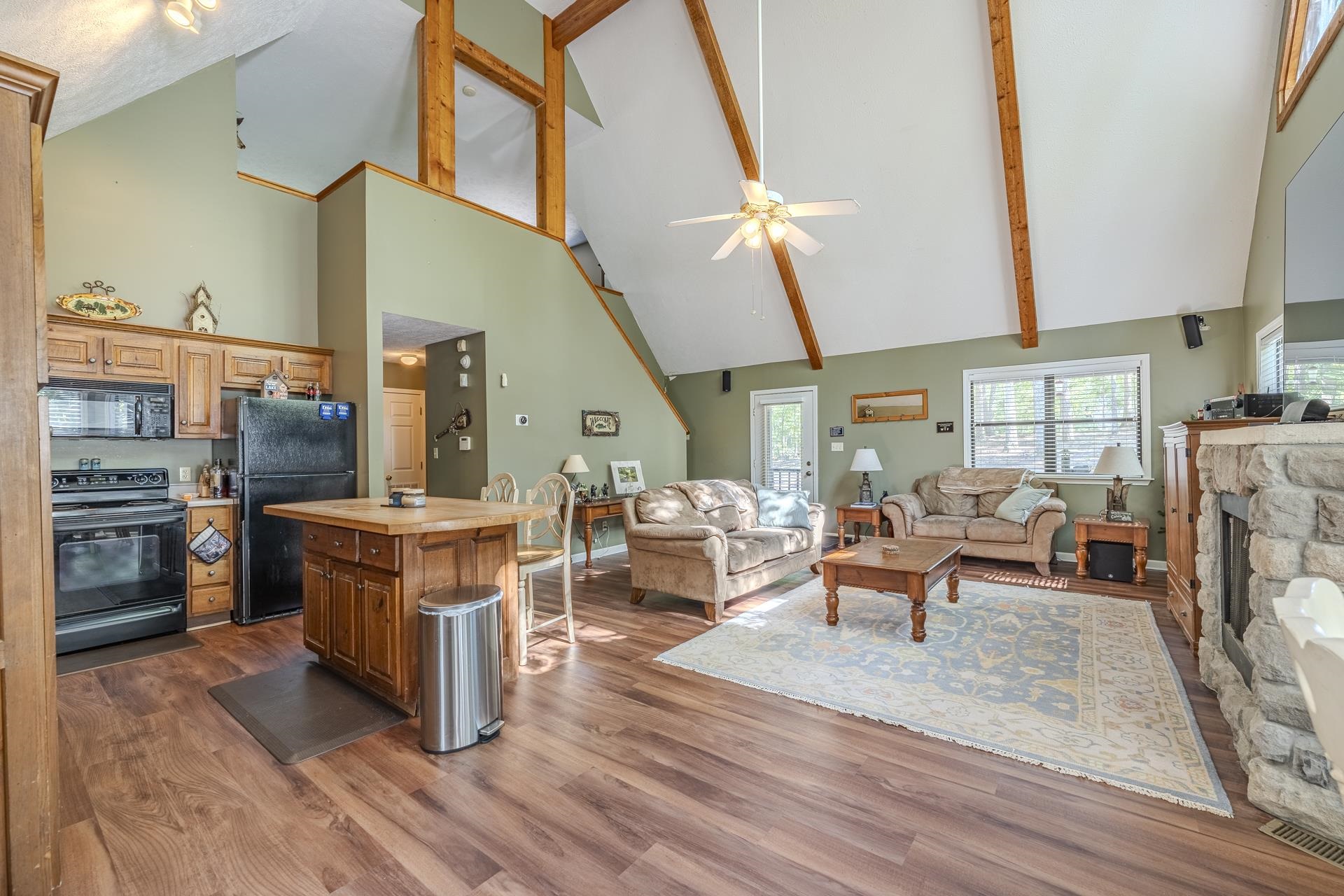 435 Murray Lane Counce, TN 38326 - Photo 9 of 34 Open concept living space featuring vaulted ceilings with exposed wood beams, wood-finish flooring, and a stone-clad fireplace