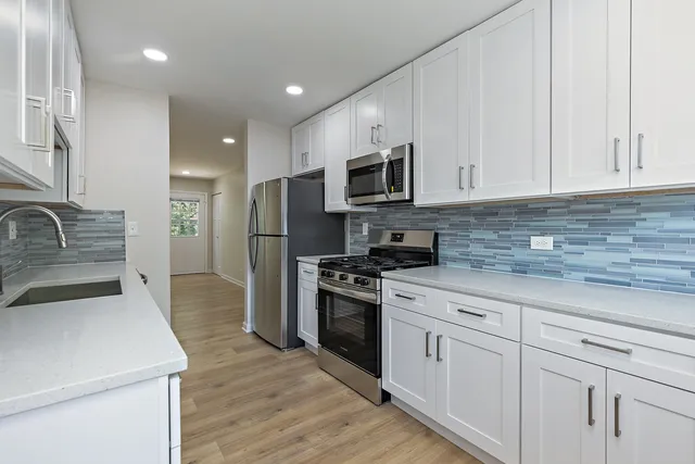 a kitchen with white cabinets and stainless steel appliances