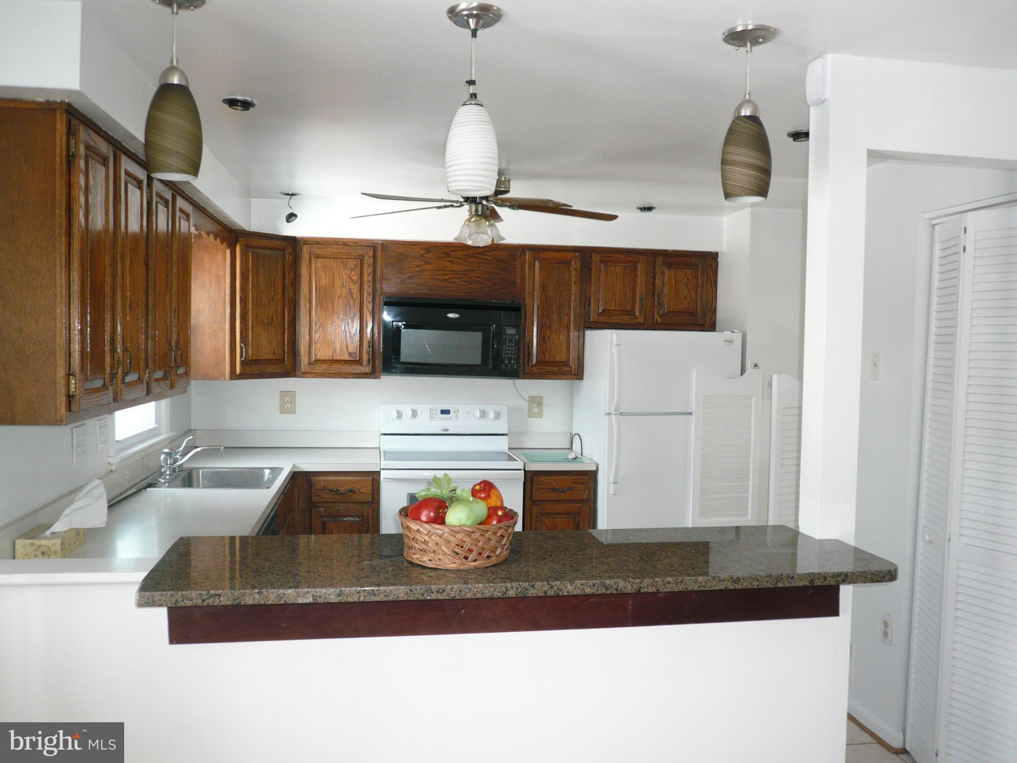 8512 Contee Road Laurel, MD 20708 - Photo 7 of 20 a kitchen with kitchen island granite countertop a sink a stove and refrigerator