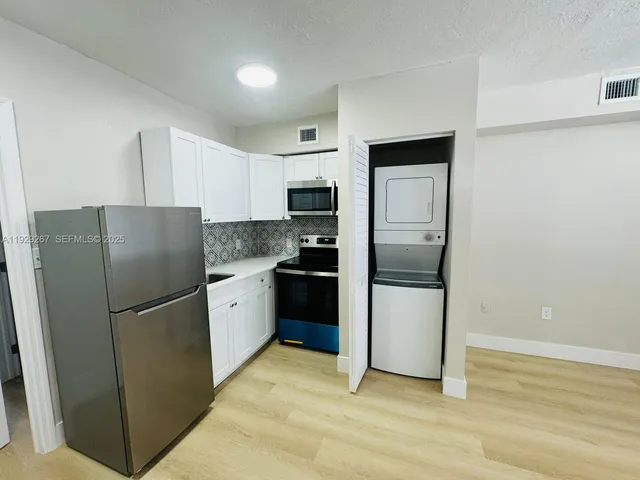 a kitchen with a refrigerator stainless steel appliances wooden floor and cabinets