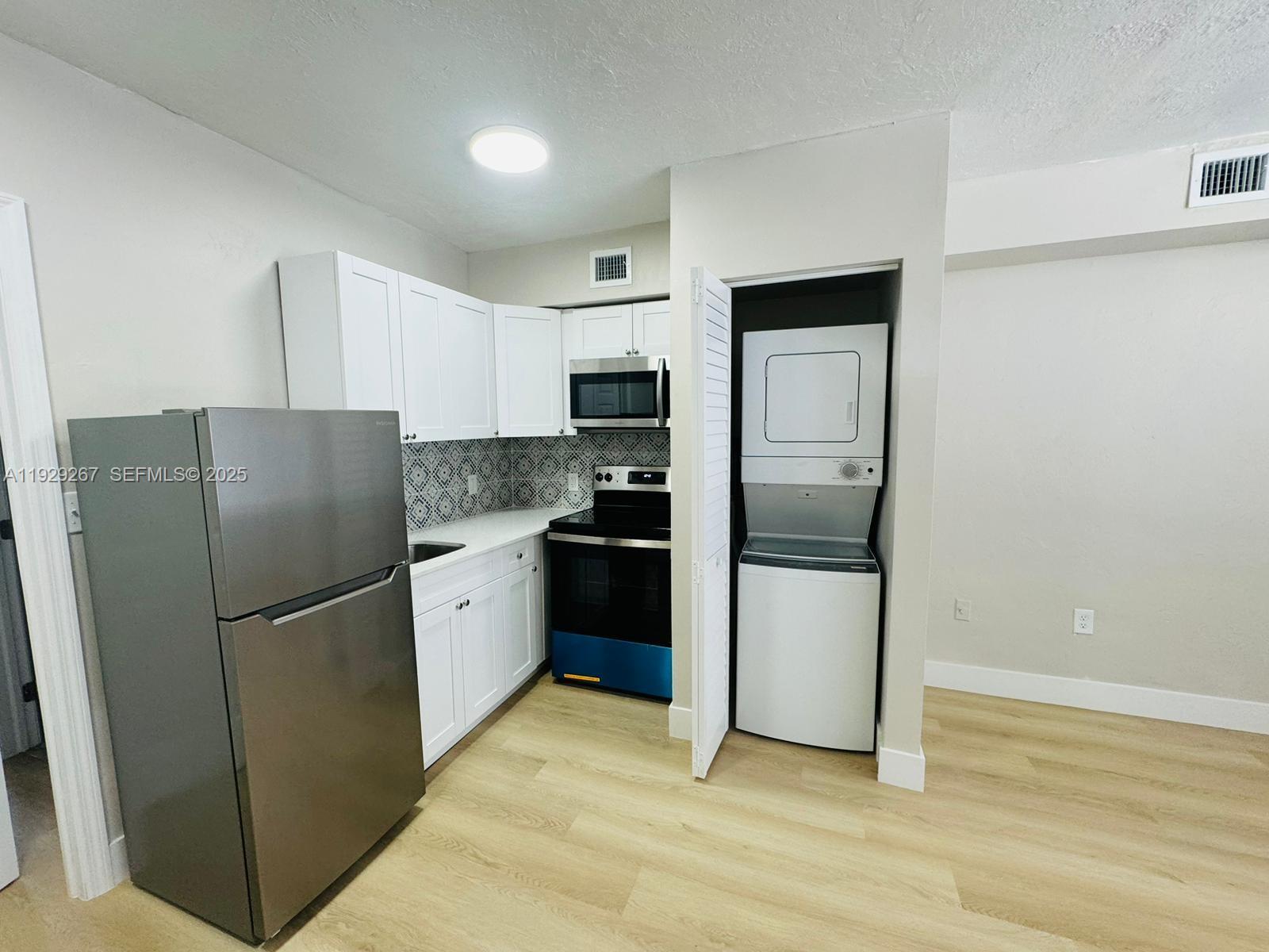 2940 West Flagler Street, Unit 4 Miami, FL 33135 - Photo 1 of 13 a kitchen with a refrigerator stainless steel appliances wooden floor and cabinets