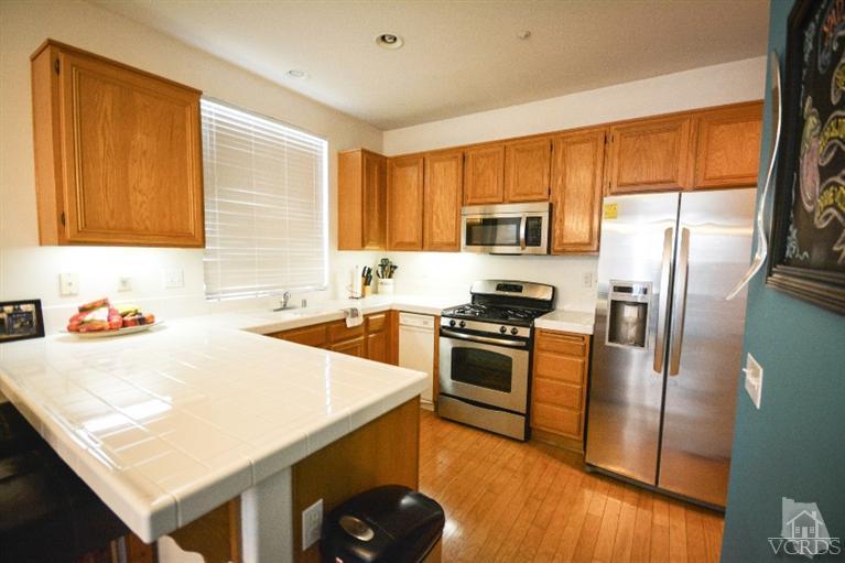 843 Pivot Point Way Oxnard, CA 93035 - Photo 7 of 21 a kitchen with granite countertop a stove top oven a sink dishwasher and a refrigerator with wooden floor