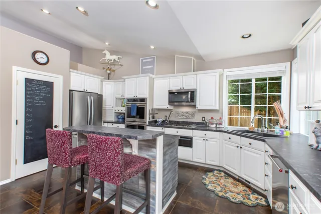 a kitchen with stainless steel appliances a stove a sink a microwave a refrigerator and cabinets