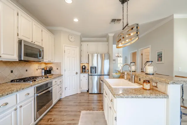 a kitchen with stainless steel appliances granite countertop a sink a stove top oven a refrigerator cabinets and living room view