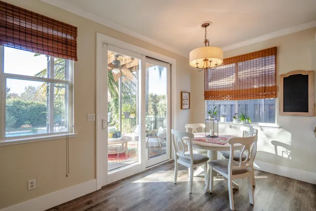 a dining room with wooden floor a chandelier a glass table and chairs