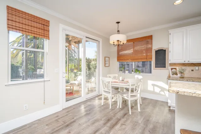a dining room with wooden floor a chandelier a wooden table and chairs