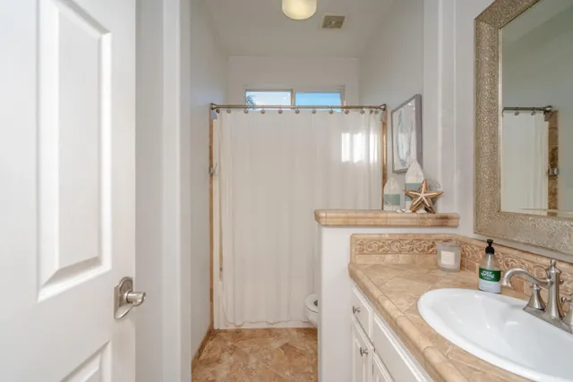 a bathroom with a granite countertop sink a mirror and shower