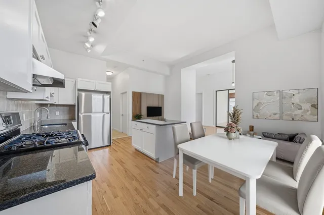 a large kitchen with a table chairs stainless steel appliances and cabinets