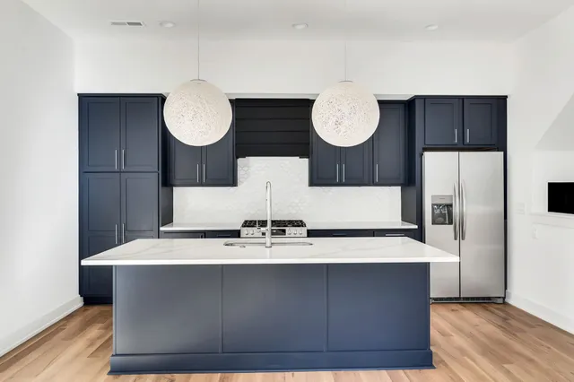 a kitchen with stainless steel appliances granite countertop a sink a stove and a wooden floors