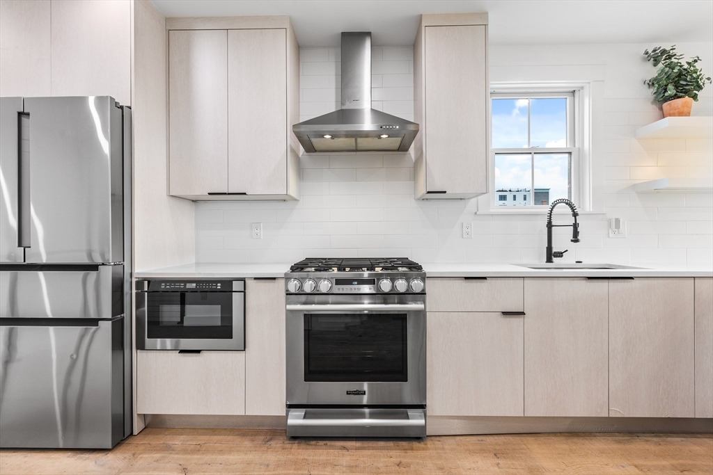 360 Athens Street, Unit 360 Boston, MA 02127 - Photo 2 of 27 a kitchen with stainless steel appliances granite countertop a stove a refrigerator and a sink