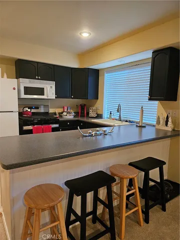 a kitchen with stainless steel appliances granite countertop a sink counter space and chairs in it
