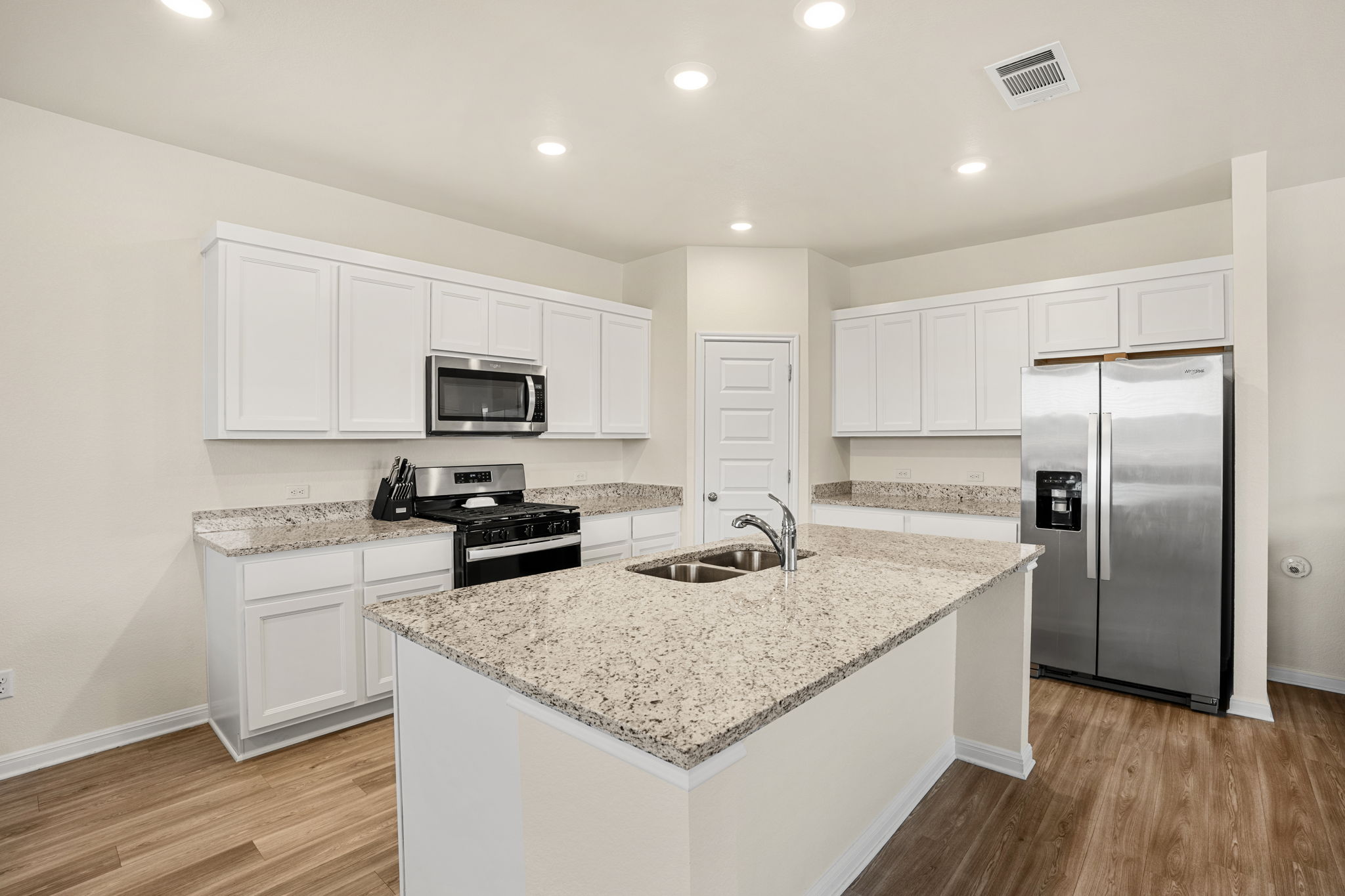 148 Hidalgo Lane Elgin, TX 78621 - Photo 10 of 38 Sleek stainless steel appliances complement the bright white cabinetry and granite countertops in this functional kitchen.