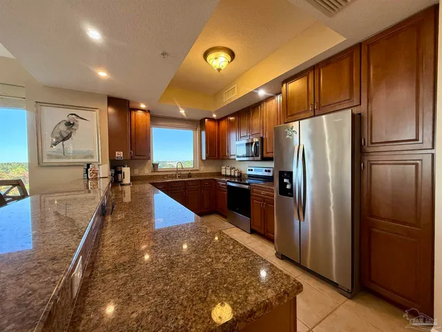 a kitchen with stainless steel appliances granite countertop a refrigerator a sink and a stove
