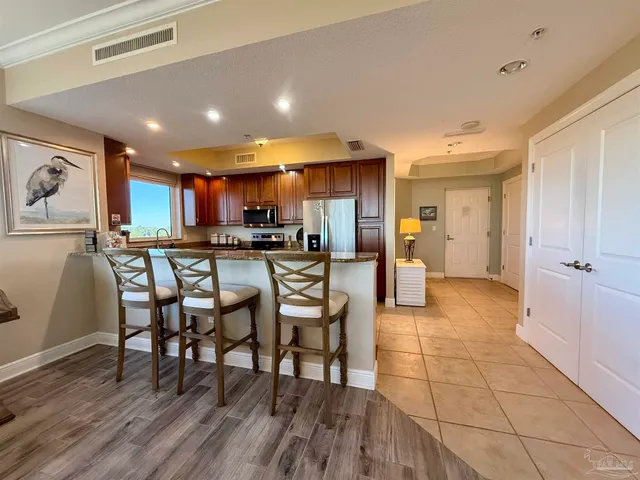 a kitchen with stainless steel appliances kitchen island granite countertop a refrigerator and a stove top oven