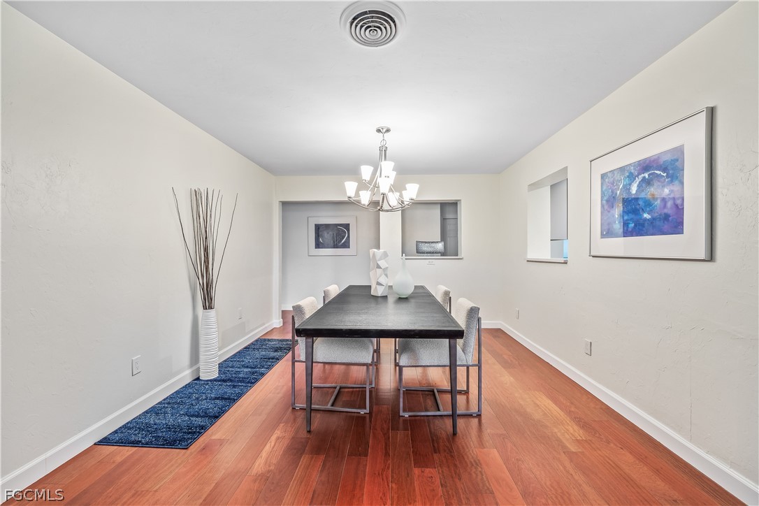 3209 West Riverside Drive Fort Myers, FL 33901 - Photo 13 of 31 a dining room with wooden floor a chandelier a wooden table and chairs