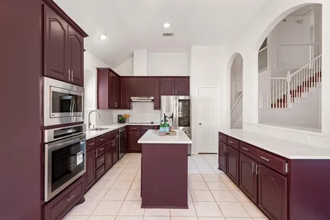 a large kitchen with stainless steel appliances granite countertop a stove top oven a sink dishwasher and a refrigerator