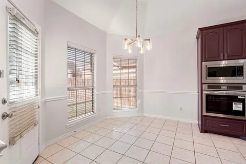 a view of an empty room with a window and kitchen view