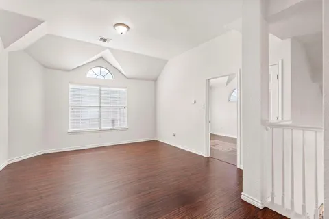 an empty room with wooden floor cabinet and windows