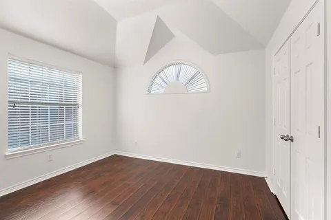 an empty room with wooden floor and window