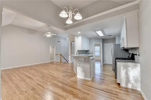 a large kitchen with kitchen island a island wooden floors stainless steel appliances and a counter space