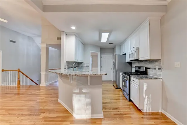a kitchen with stainless steel appliances granite countertop a stove and a white cabinets