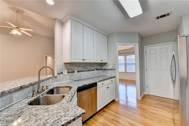 a kitchen with granite countertop white cabinets and stainless steel appliances