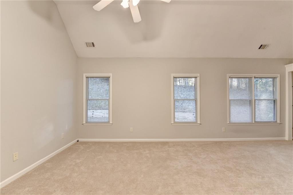 655 Golden Meadows Lane Suwanee, GA 30024 - Photo 28 of 72 an empty room with windows and chandelier fan