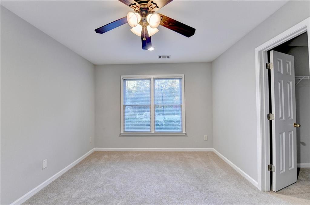 655 Golden Meadows Lane Suwanee, GA 30024 - Photo 55 of 72 an empty room with a chandelier fan and windows