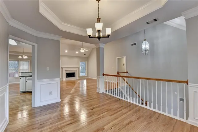 a view of a hallway with wooden floor and a chandelier
