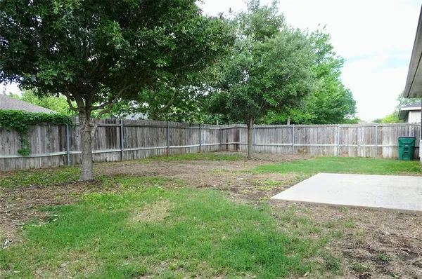 a view of a house with a yard plants and large tree