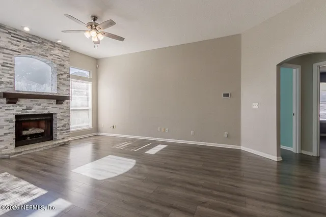 a view of an empty room with wooden floor fireplace and a window