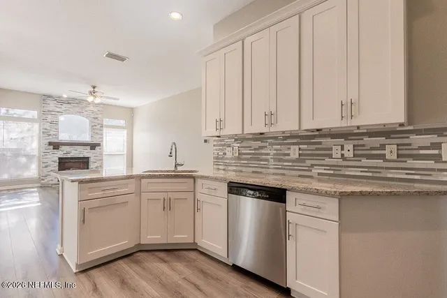 a kitchen with stainless steel appliances granite countertop a sink and dishwasher a stove top oven with white cabinets