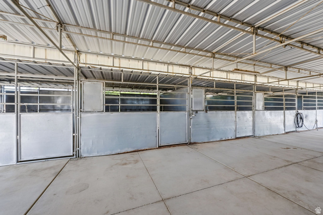 3732 Campbell Road Tooele, UT 84074 - Photo 55 of 69 Covered barn structure featuring a corrugated metal roof, concrete flooring, and multiple metal stalls with gates