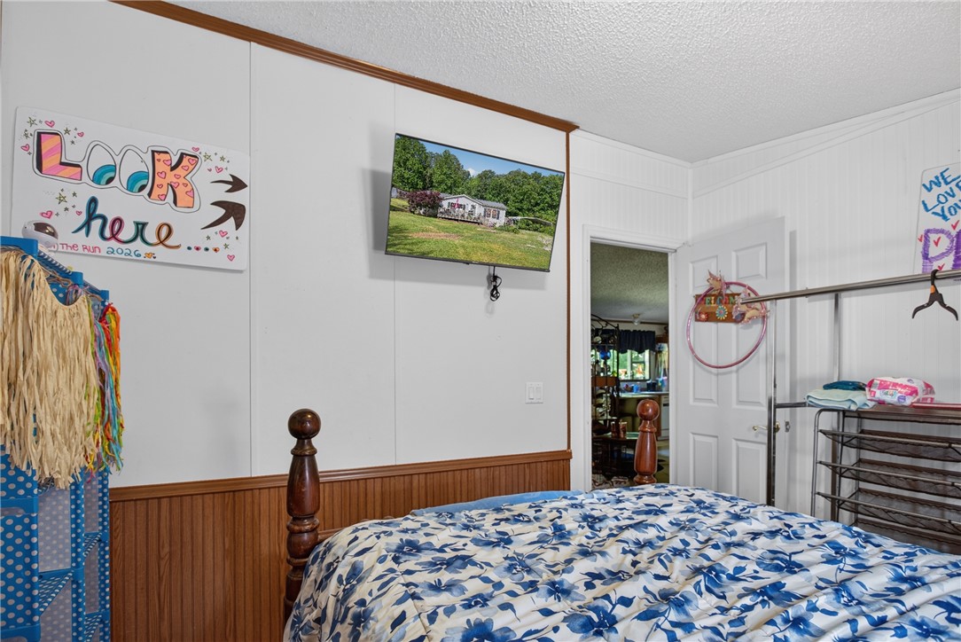 418 Chauga Road Westminster, SC 29693 - Photo 22 of 38 Relax in this comfortable bedroom, featuring a classic wooden bed frame and clean white walls with a beadboard accent.