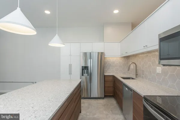 a kitchen with stainless steel appliances granite countertop a sink and a refrigerator