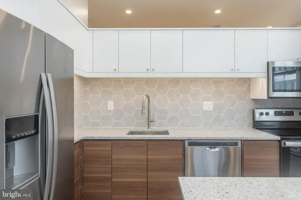 a kitchen with stainless steel appliances granite countertop a refrigerator a sink and white cabinets