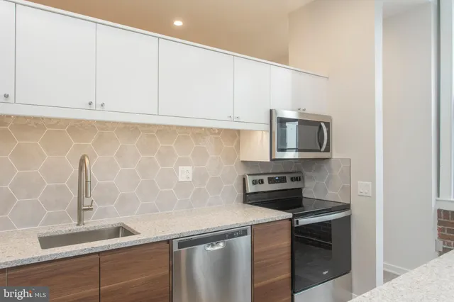 a kitchen with granite countertop white cabinets and stainless steel appliances