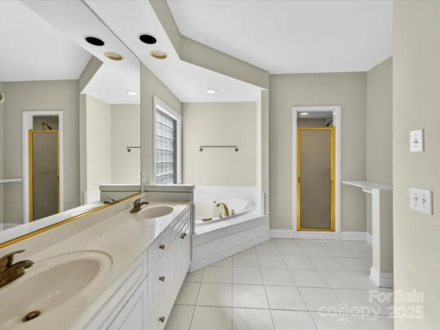 a spacious bathroom with a tub sink and mirror