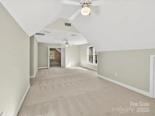 an empty room with a chandelier fan and windows