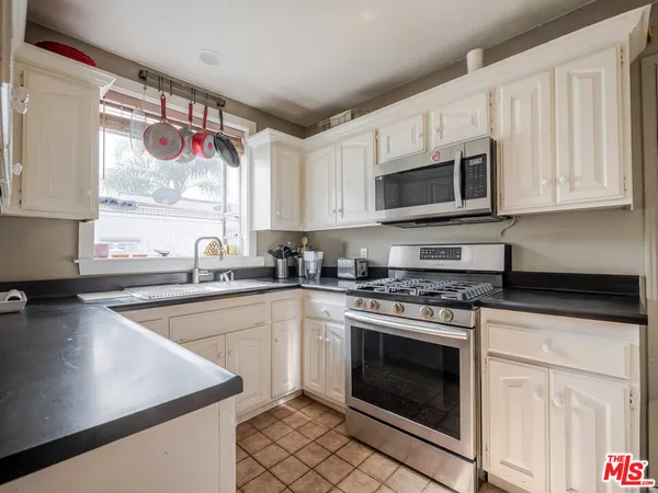 a kitchen with granite countertop a stove top oven microwave and cabinets