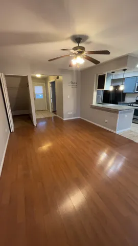 a view of an empty room with chandelier fan and a large window