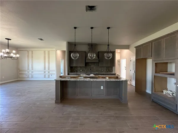 a large kitchen with stainless steel appliances a large counter top a stove and a refrigerator