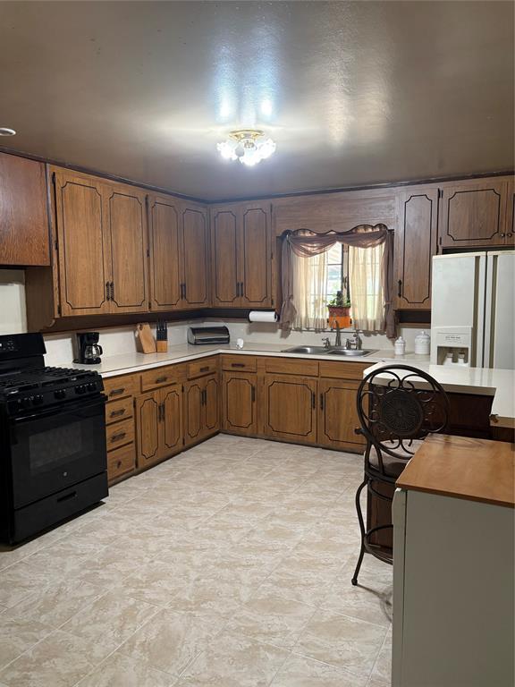 1581 Harbor Road Dallas, TX 75216 - Photo 4 of 15 U-shaped kitchen featuring wood cabinetry, solid surface countertops, and tile flooring