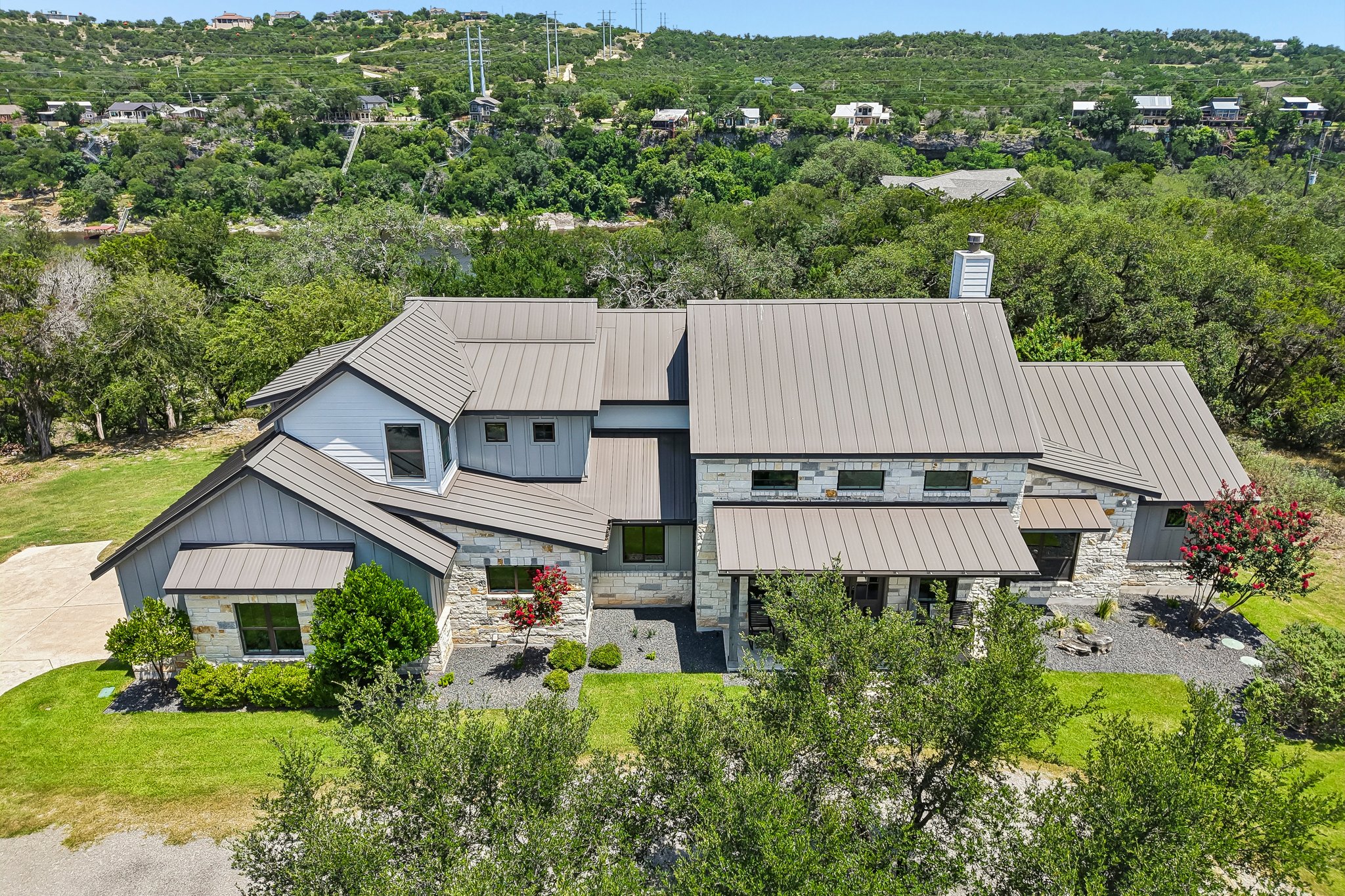 2203 Improver Road Spicewood, TX 78669 - Photo 1 of 38 Perched on a verdant hillside, this modern residence showcases striking architectural lines and a sleek metal roof.
