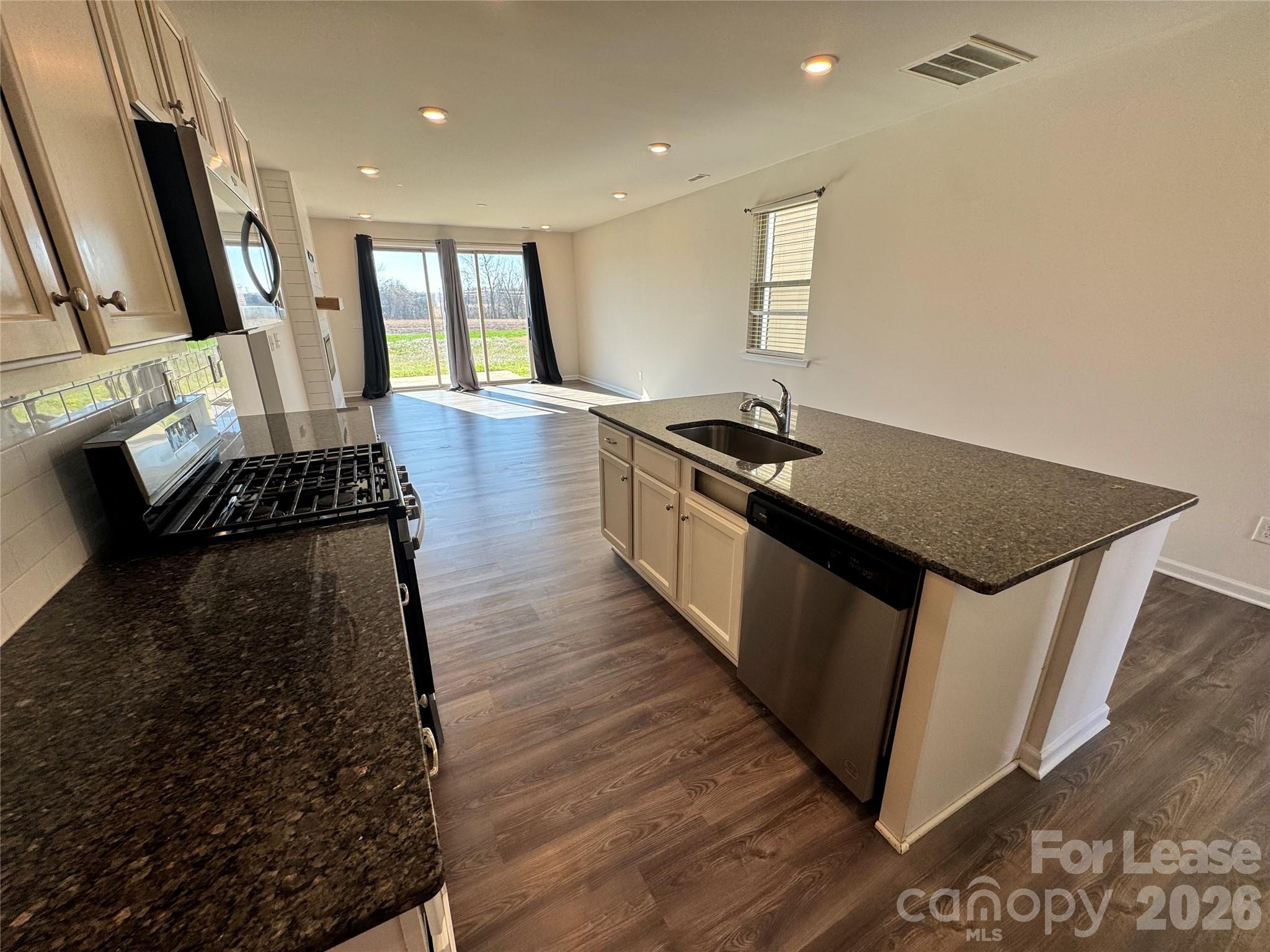 1007 Maylen Trace Monroe, NC 28110 - Photo 15 of 34 a kitchen with granite countertop a stove and wooden floor