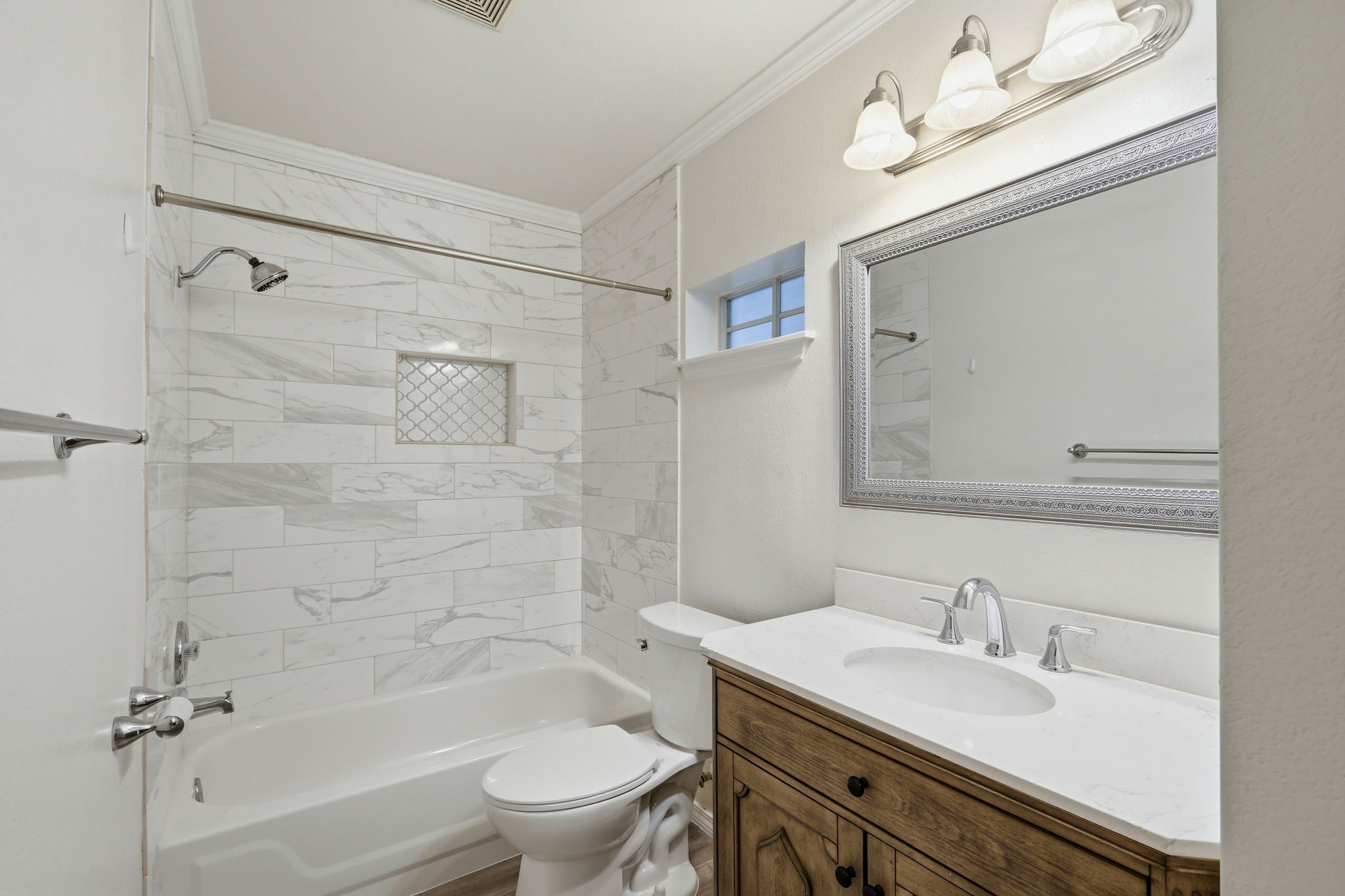 1005 Rolling Ridge Drive Round Rock, TX 78665 - Photo 11 of 18 A well-appointed bathroom featuring elegant white marble-patterned tile and a classic wood vanity.