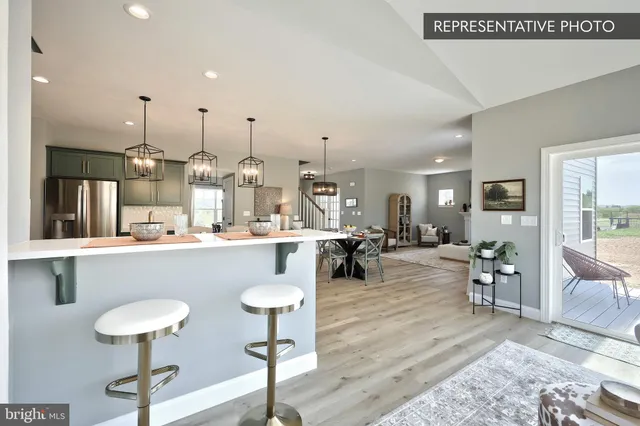 a living room with couches and kitchen view with wooden floor