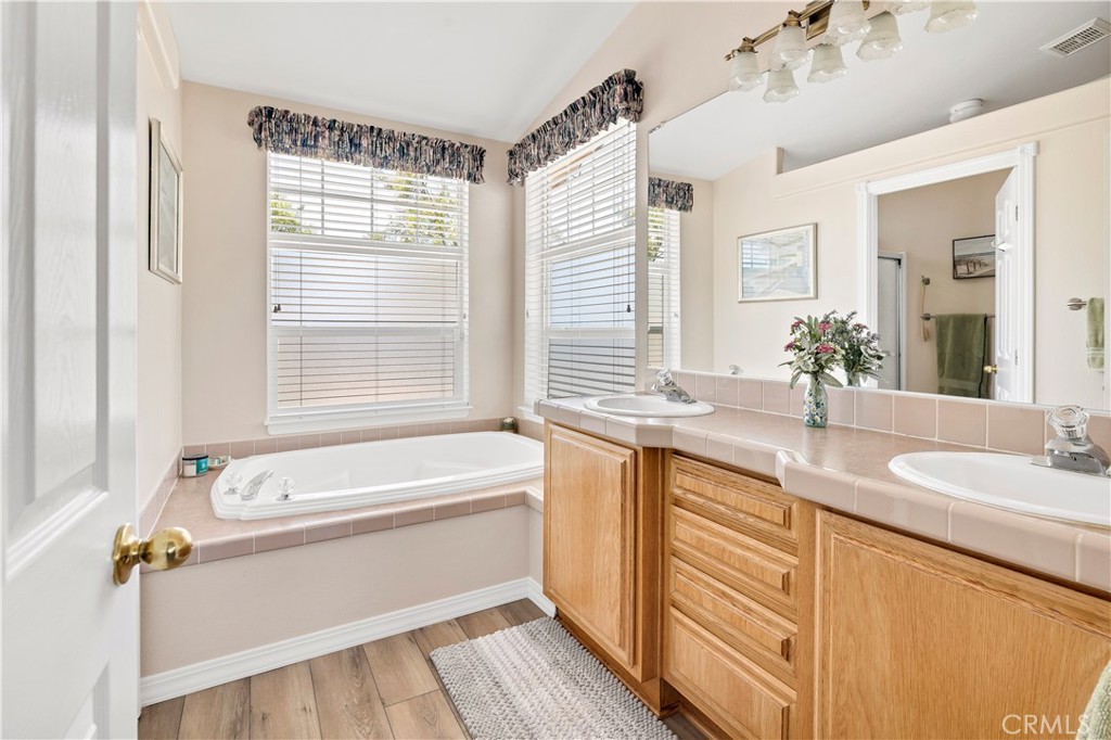 39597 Calle Escalona Temecula, CA 92592 - Photo 29 of 61 a bathroom with a tub a sink and a large mirror
